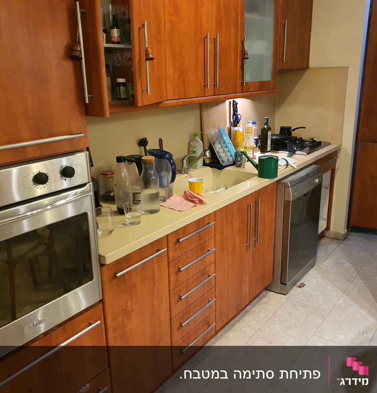 מטבח עם כיור, כלים ומוצרי ניקוי על השיש